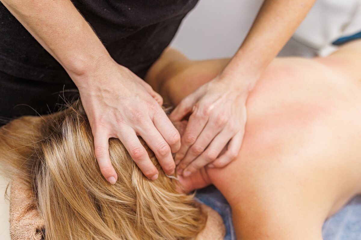 Therapist performing a neck and upper back massage during treatment