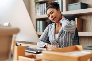 Office worker experiencing neck discomfort while working at a computer.