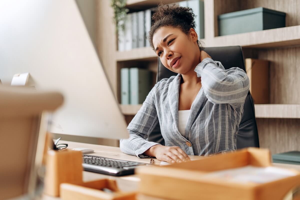 Office worker experiencing neck discomfort while working at a computer.