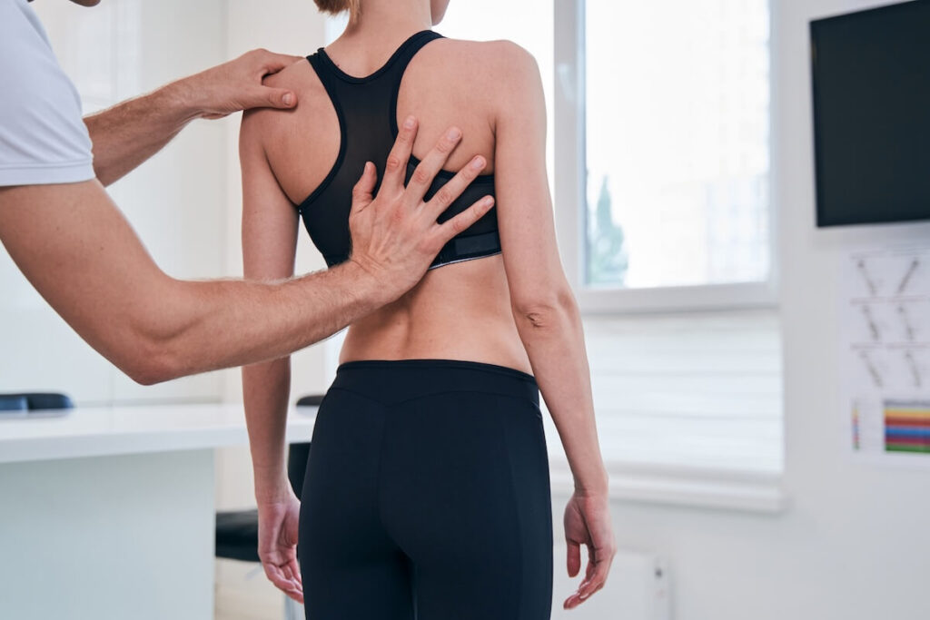 Therapist evaluating a woman’s back alignment and muscle condition.