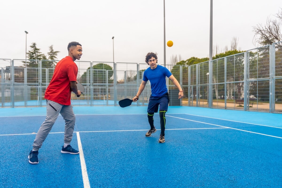 Two men actively playing pickleball on an outdoor court