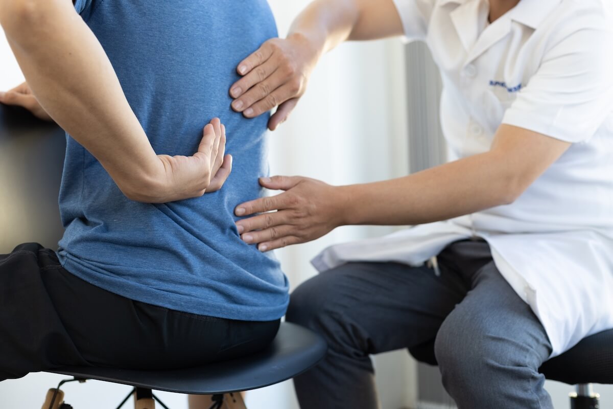 octor examining a patient’s lower back to assess pain and discomfort.