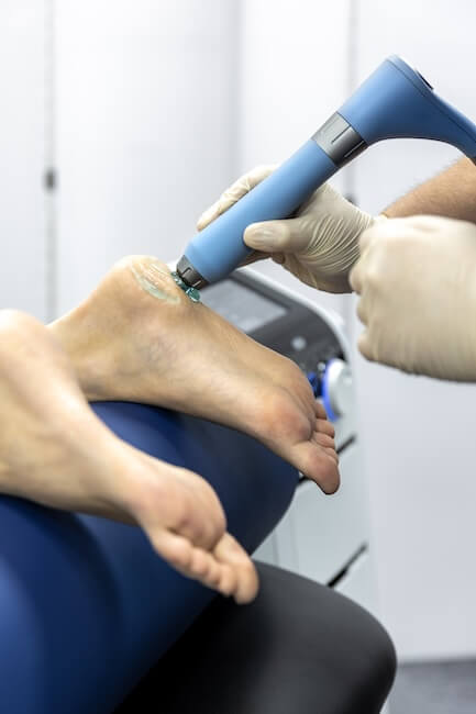 physical therapist applying shockwave therapy on patients foot