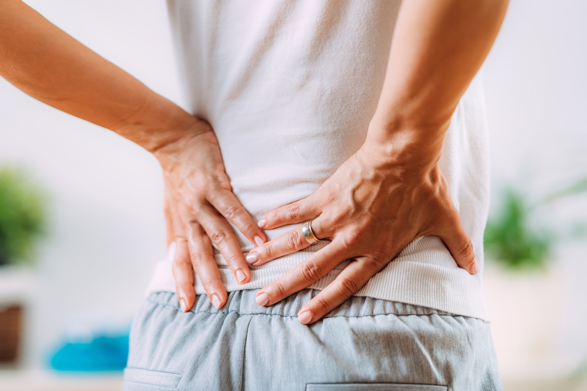 Person holding their lower back, indicating discomfort and sciatic nerve pain.