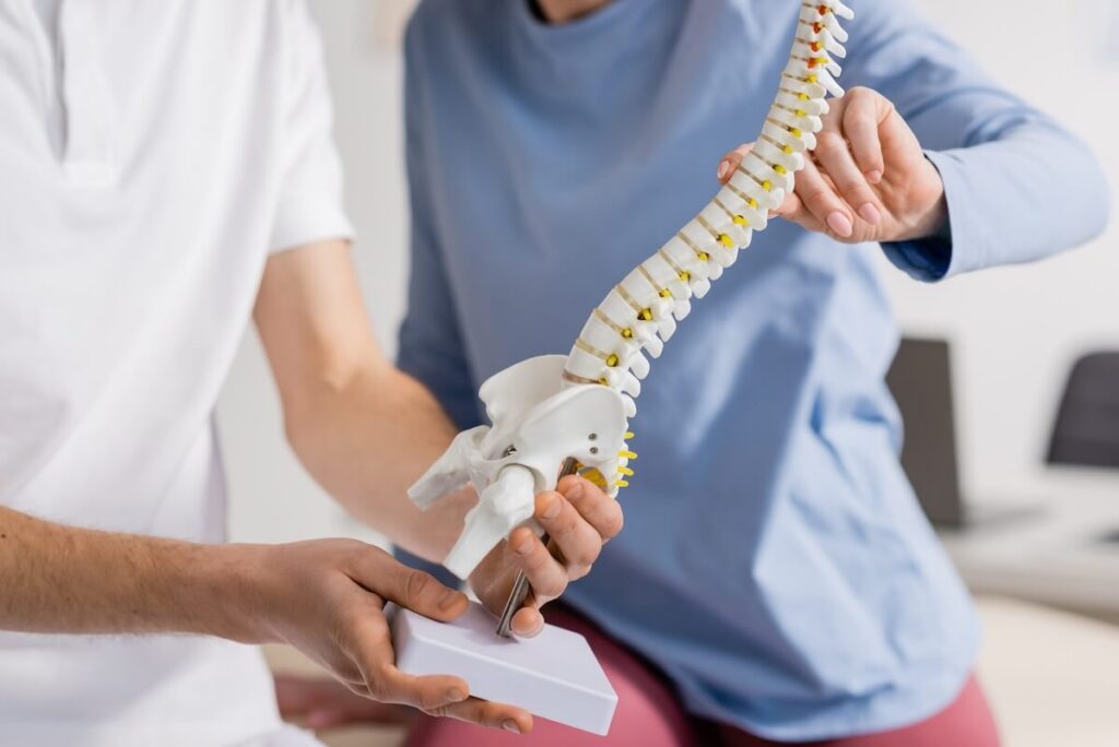 Doctor using spine model to explain spinal stenosis to patient.